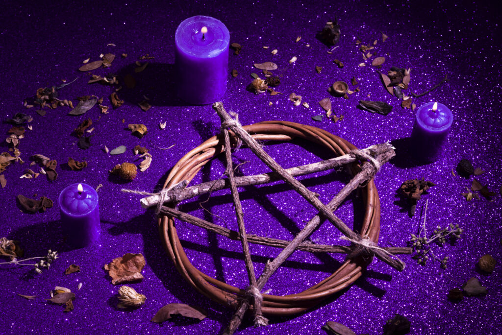 Imagem ilustrativa sobre ser um mago, mostrando um pentagrama feito com galhos secos e velas roxas, usados em rituais da magia positiva.